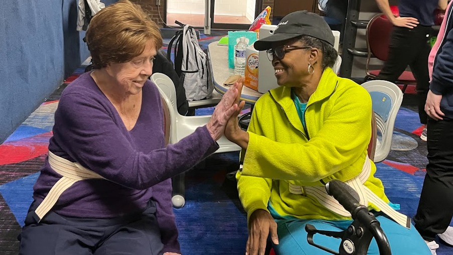 Two occupational therapy patients high fiving at the bowling alley. 