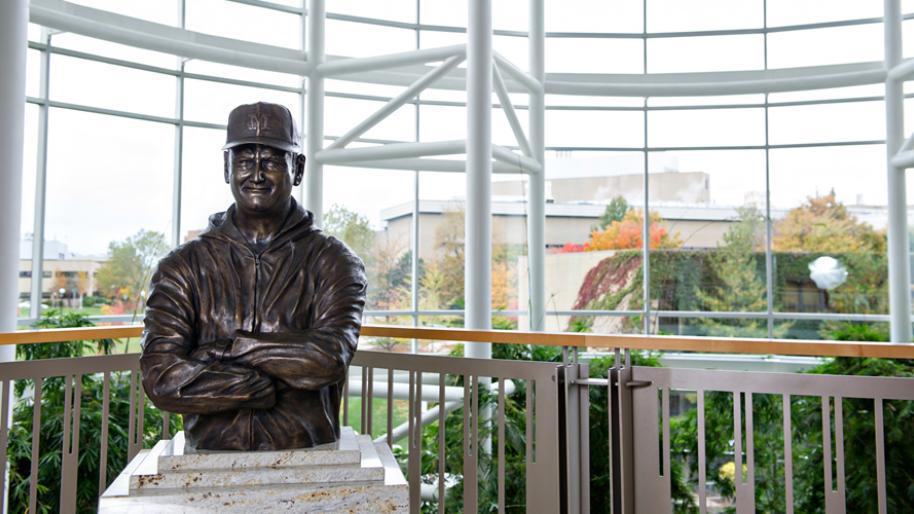 A bronze statue sitting on a pedestal in front of a large window wall