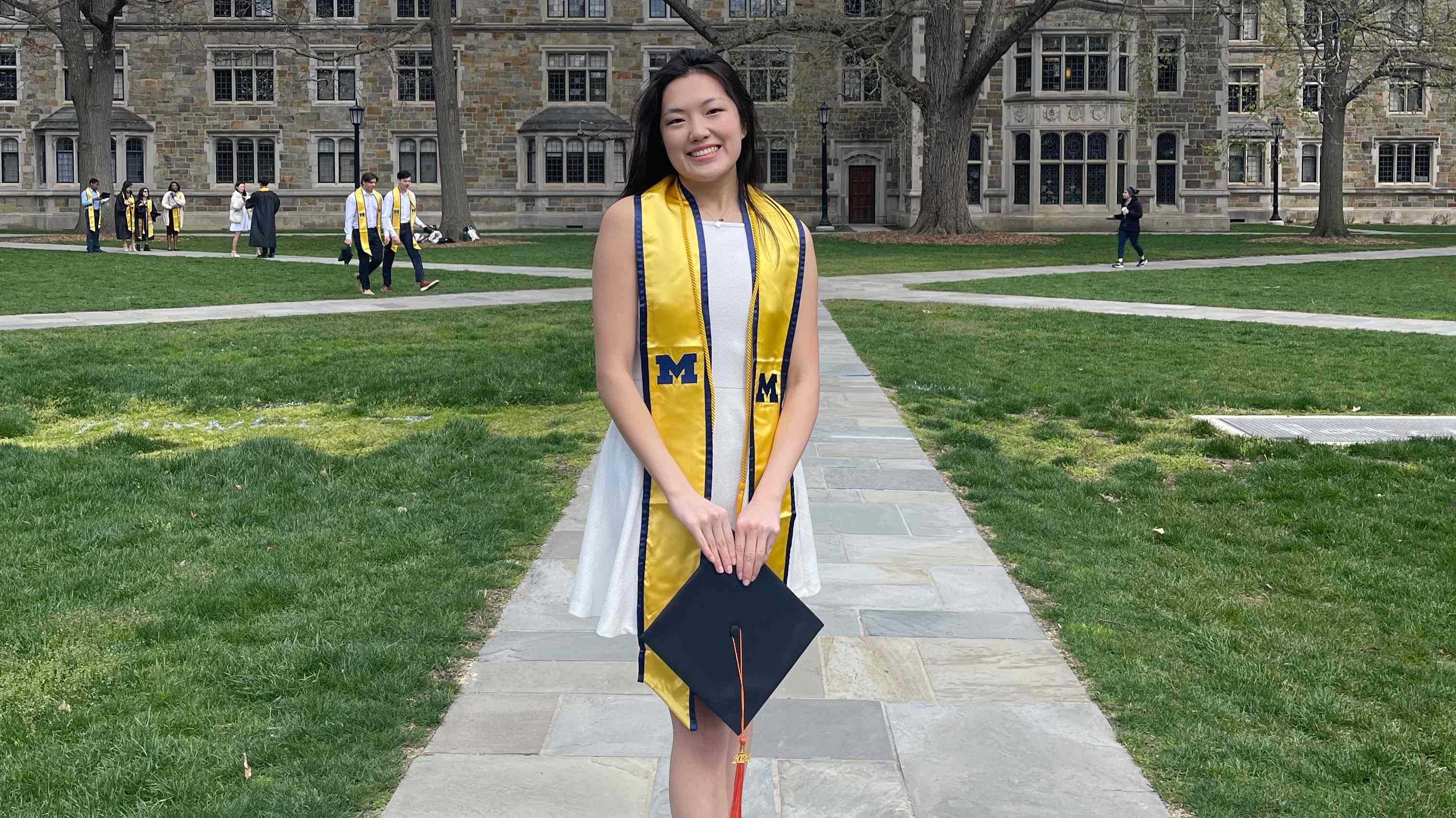 Christine Wu with graduation cap and stole standing in the Law Quad
