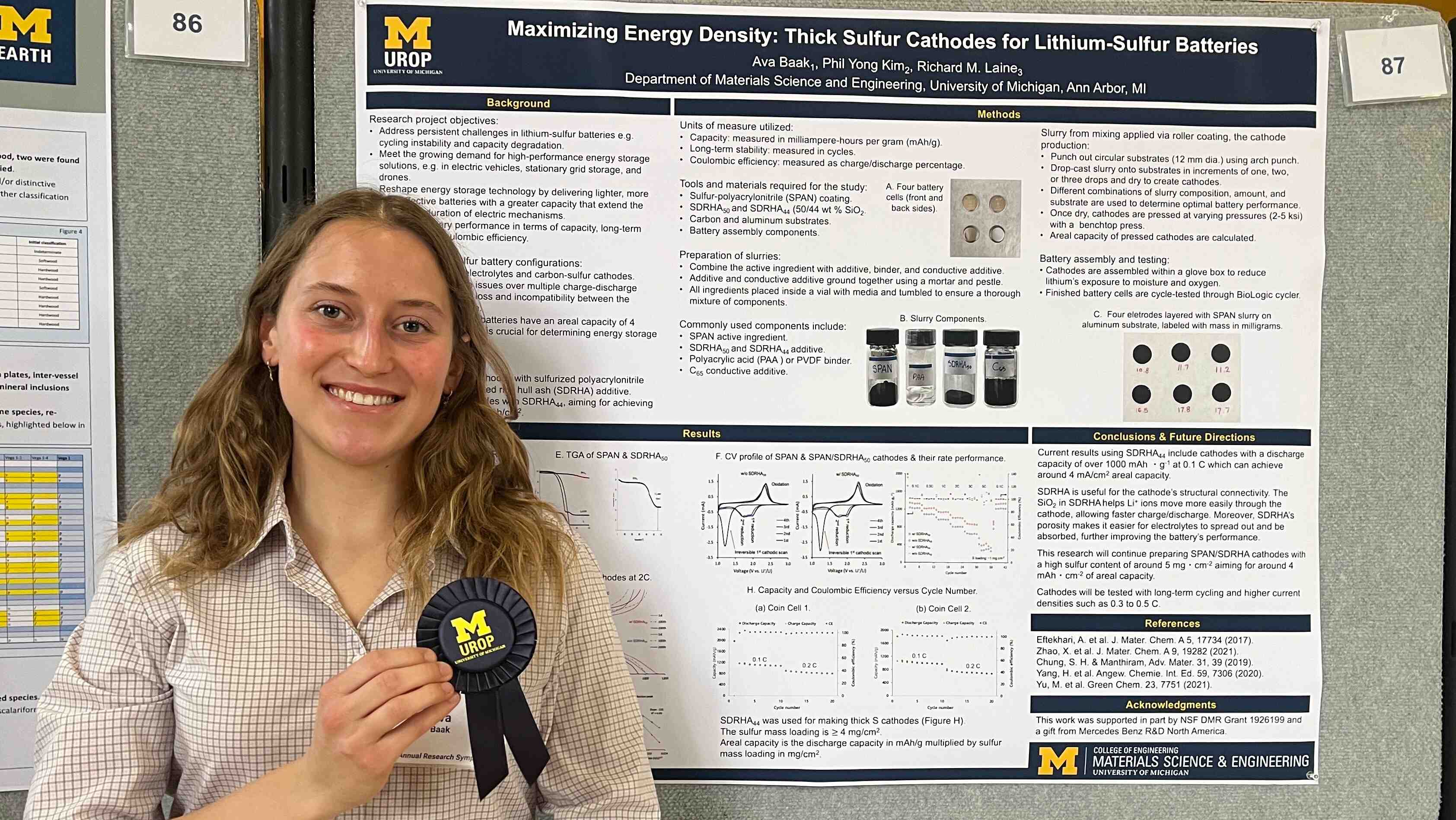 Ava Baak standing in front of a scientific poster holding a blue prize ribbon