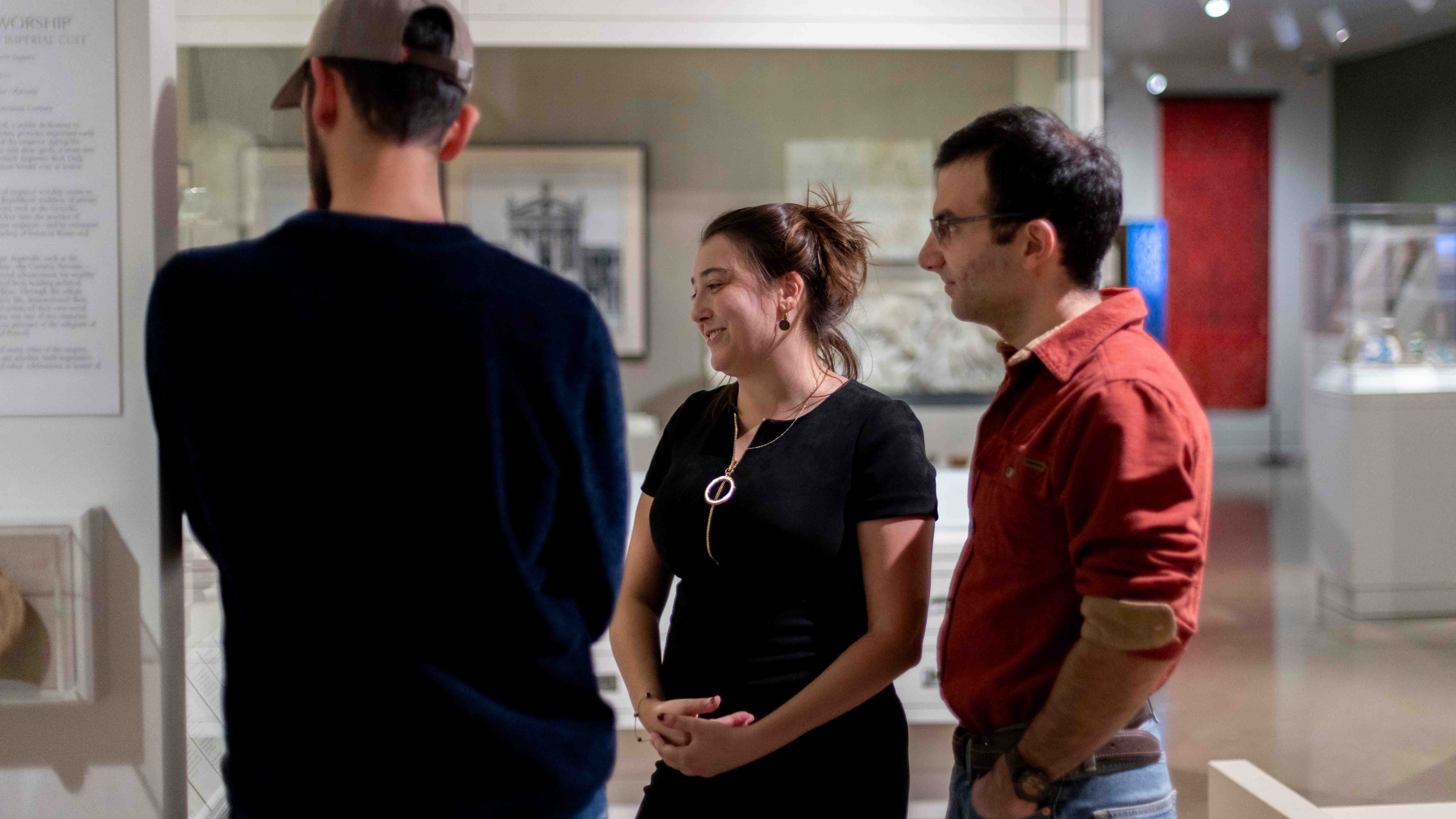 Three people looking at an exhibit at the Kelsey Museum.