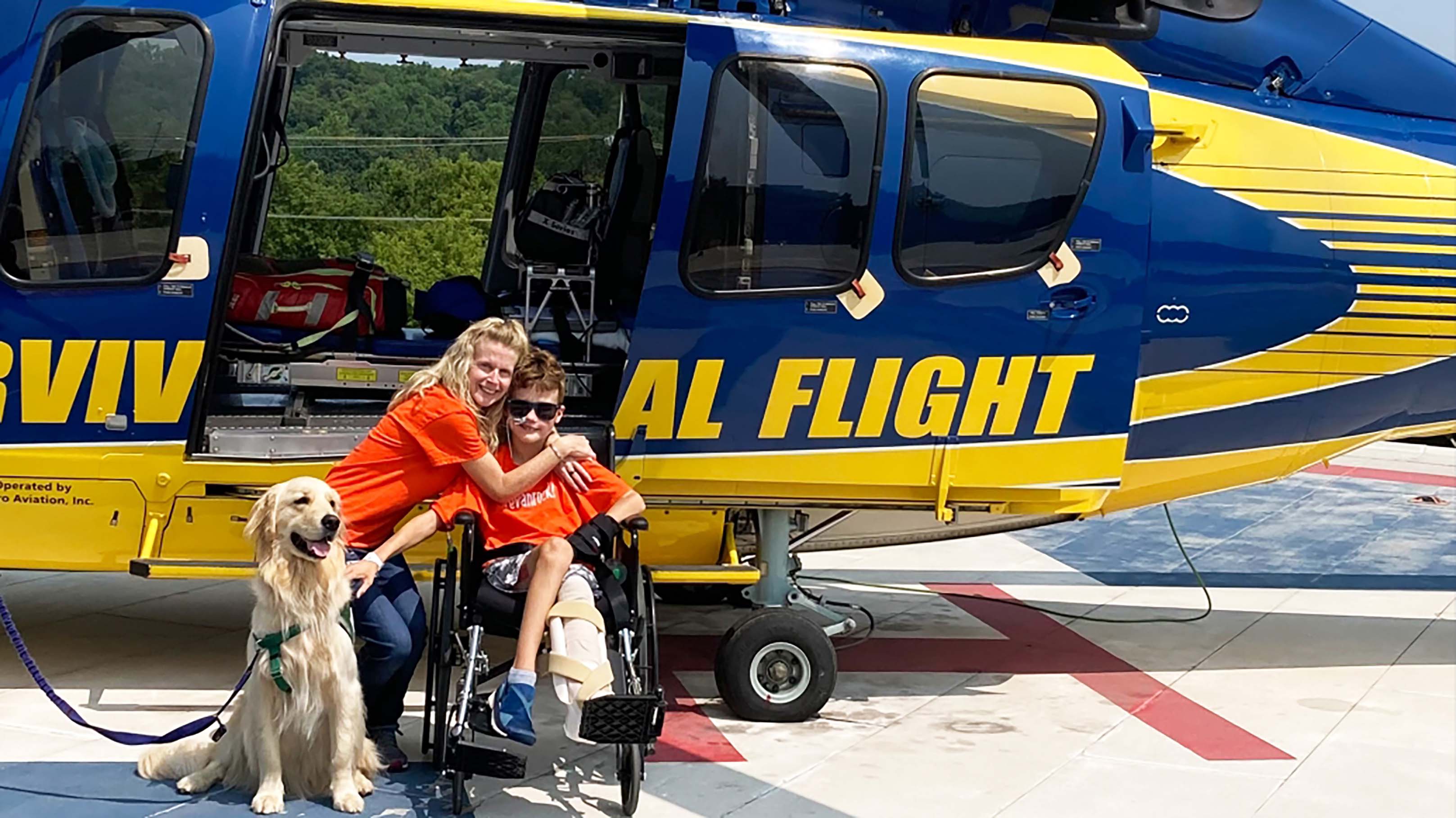 mom and son and dog in front of the survival flight helicopter