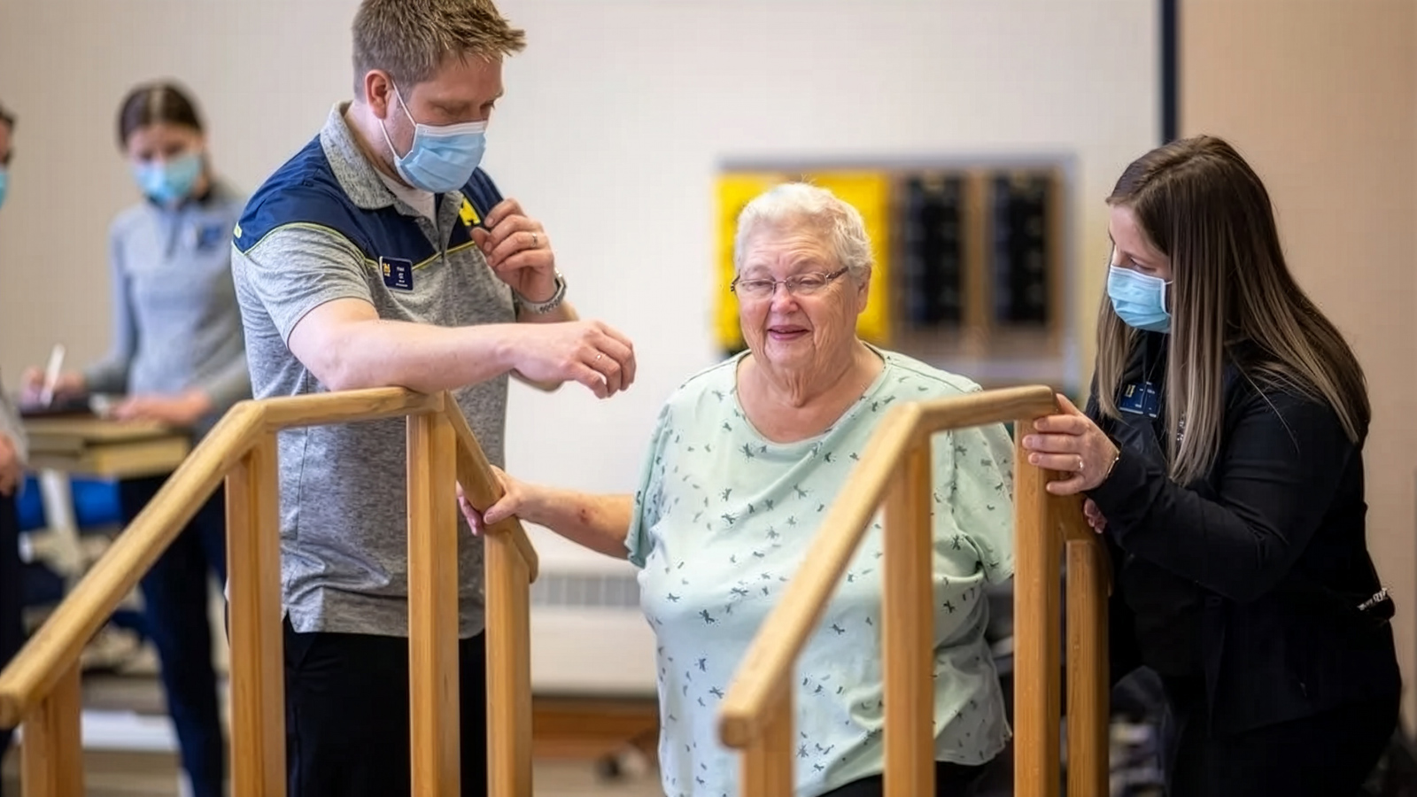 Two staffers at the HEART Clinic helping a patient climb stairs.