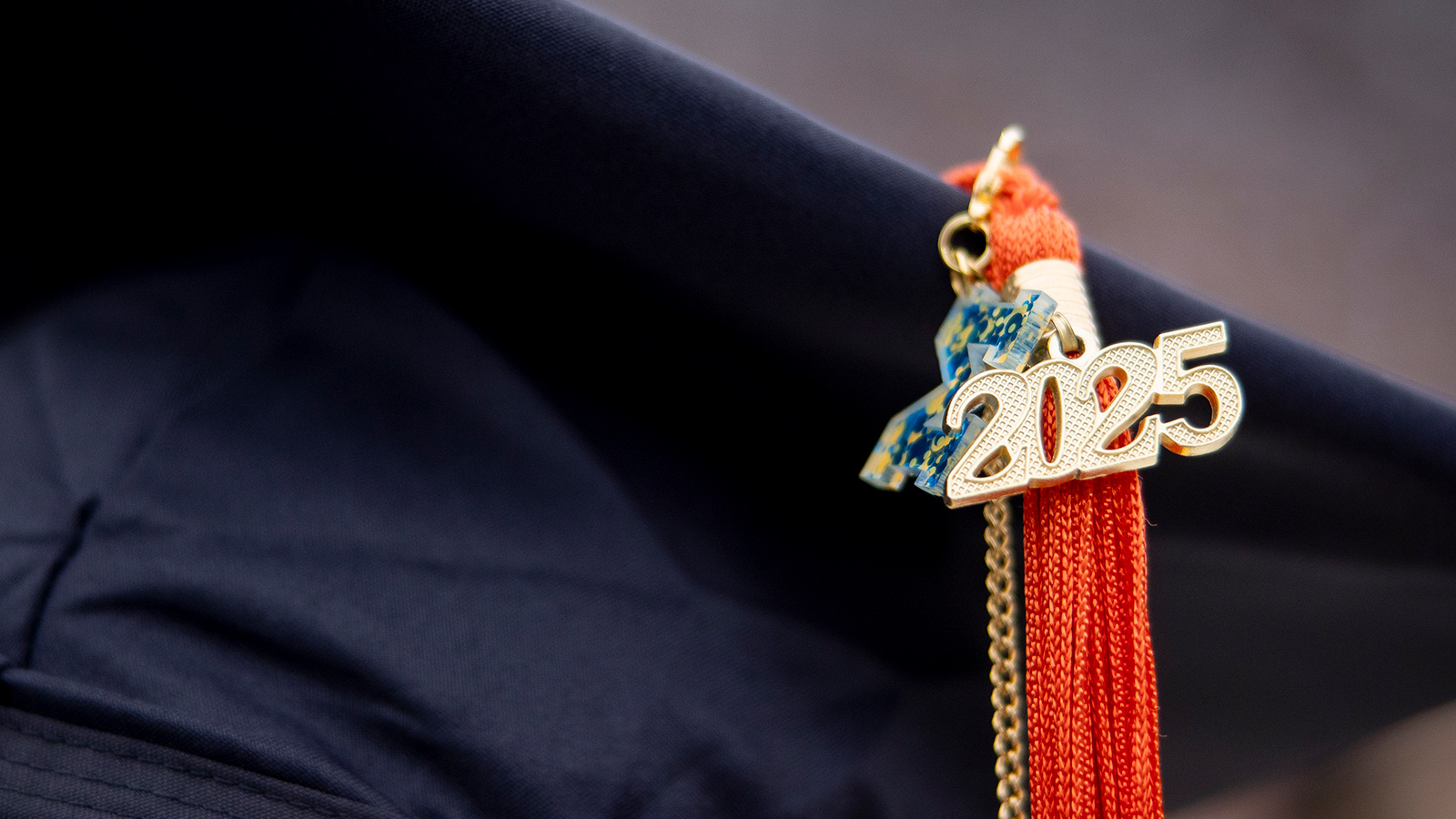 Graduation cap adorned with an orange tassel and a gold “2025” charm.