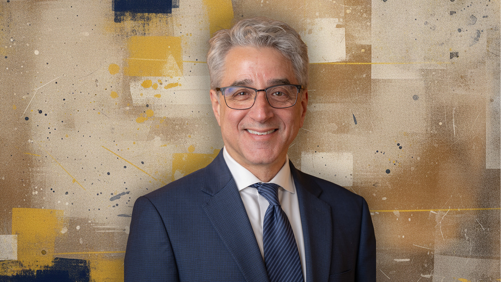 Arthur Lupia in suit and tie in front of an abstract background.
