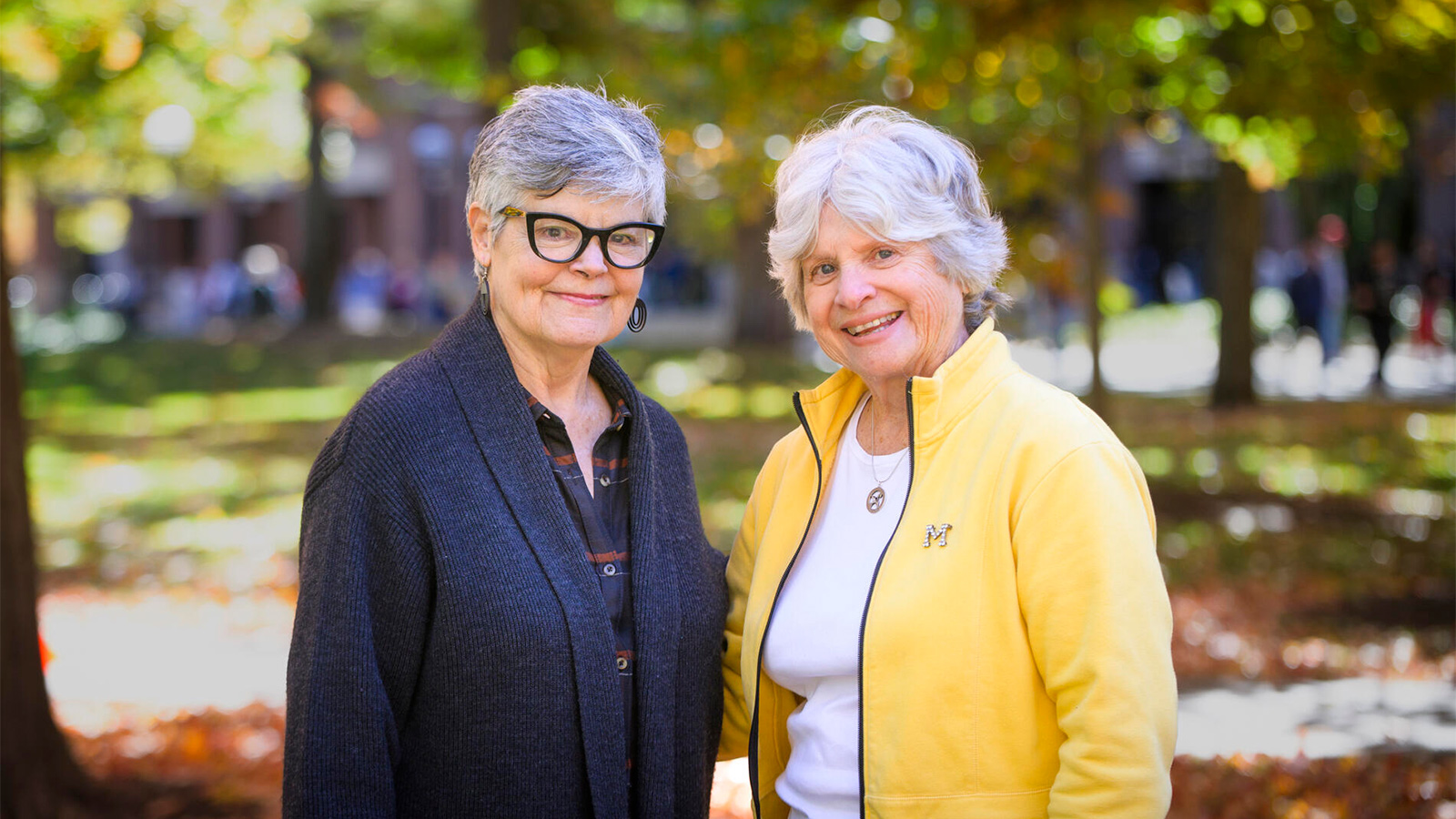 Kenlee Ray, wearing a blue sweater, and Susan Quackenbush, wearing a yellow jacket, standing outside. 