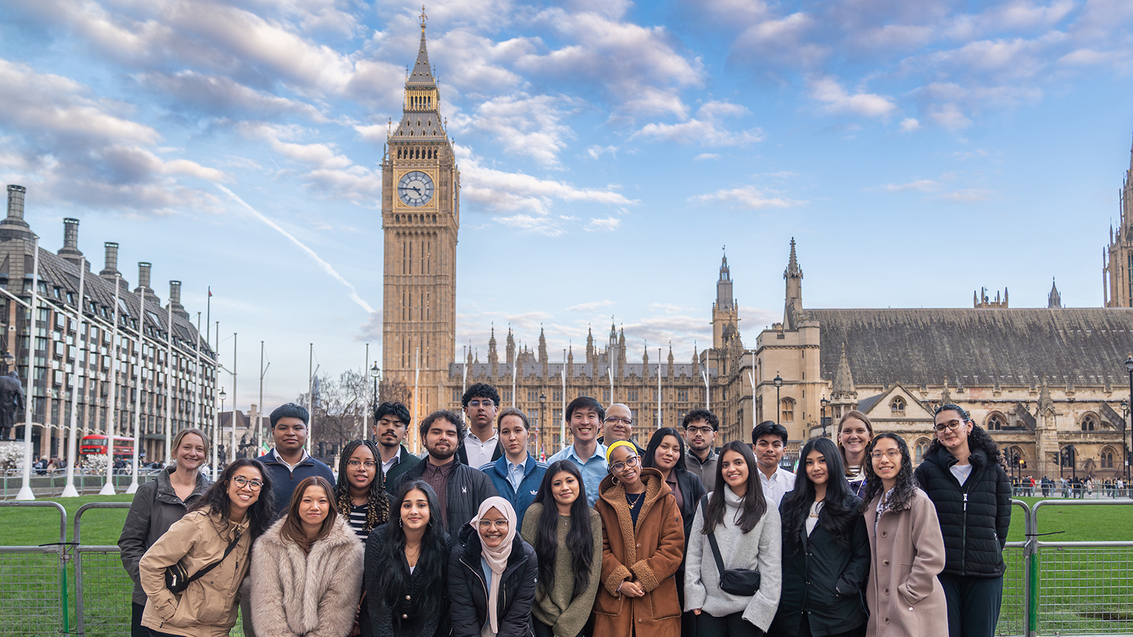 A large group poses for a photo in front of Big Ben and the Houses of Parliament in London