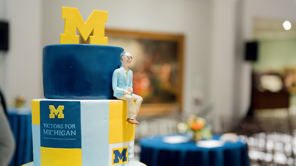 Figure of Jerry May on a maize and blue tiered cake.