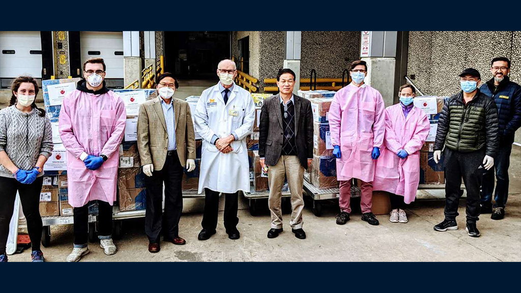 Faculty and Alumni stand next to one another wearing masks.