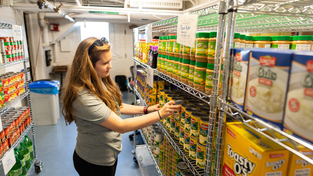 A worker stocking the shelves with canned goods.