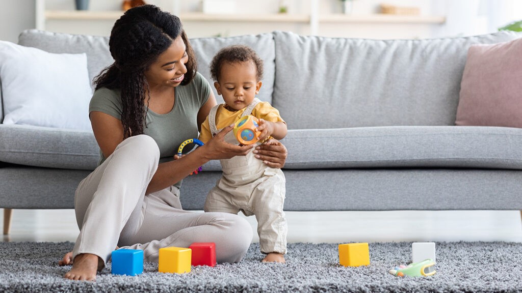 Mother playing with her kid in front of a sofa