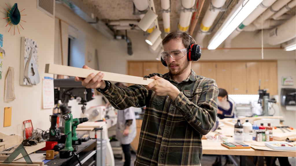 Stamps School of Art & Design student measuring a piece of wood.