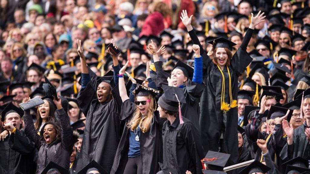 Students in graduation gowns cheering.