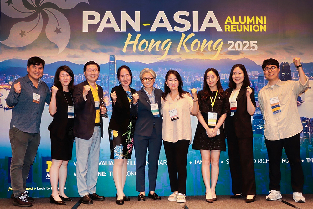 Cheering international alumni pose in from of a Pan Asia event banner.