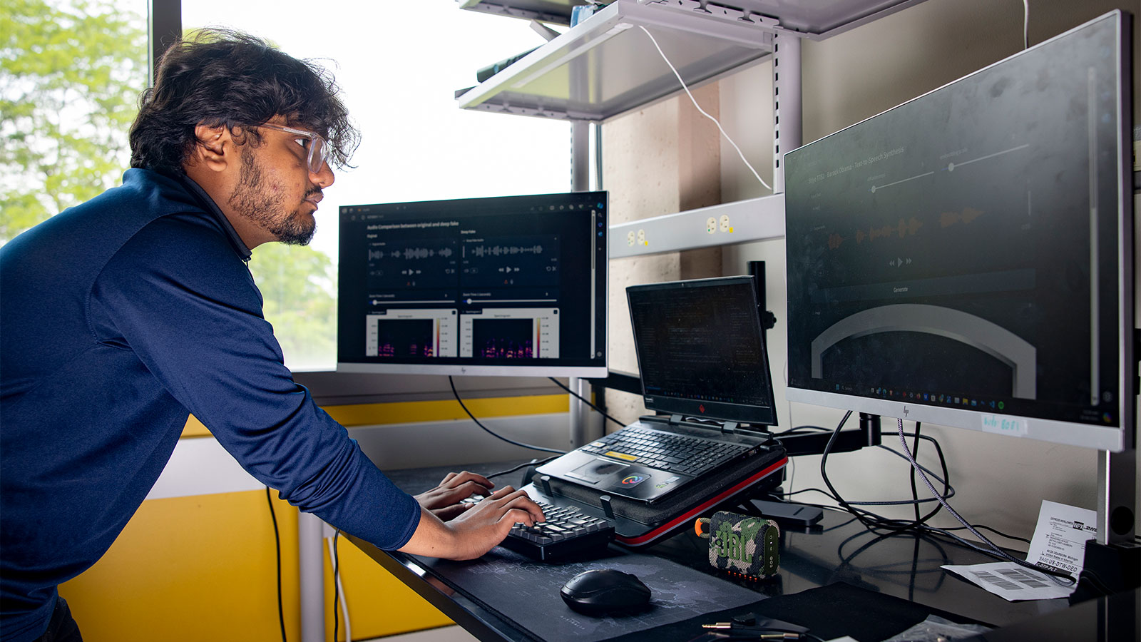 A researcher at a desk working on a computer with multiple screens.