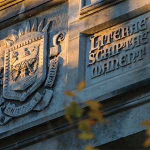 Stone crest and Latin inscription lit by evening sunlight.