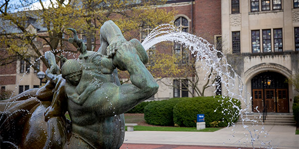 The “Sunday Morning in Deep Waters” statue sprays water in front of a campus building.