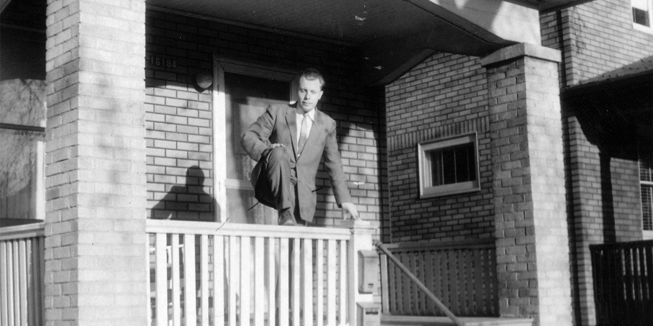 A man standing on a porch outside of a house.