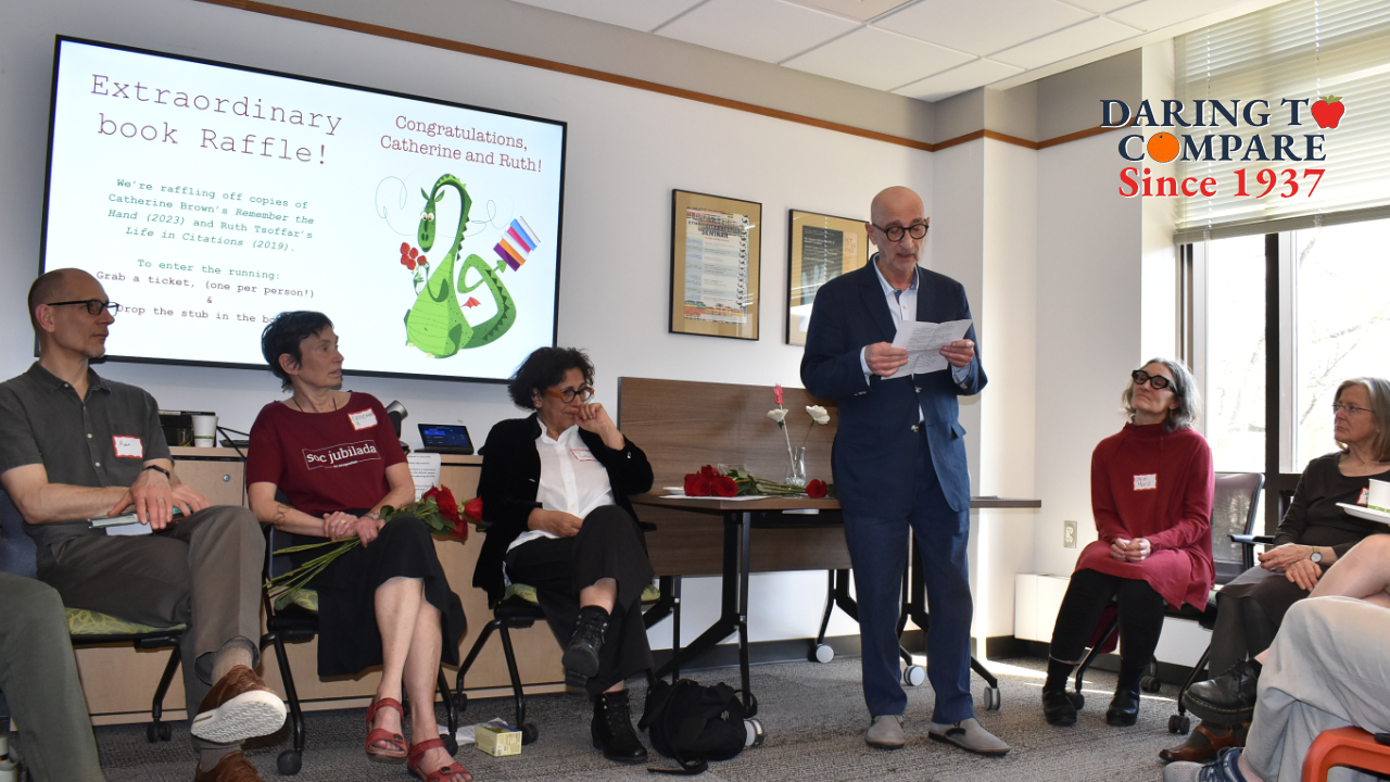 A man reads from a paper to seated attendees at a Comparative Literature anniversary gathering