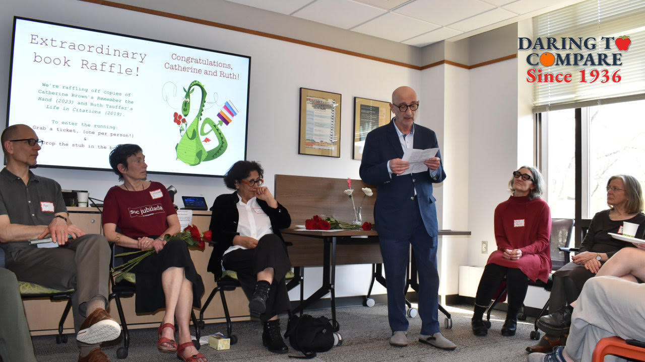 A man reads from a paper to seated attendees at a Comparative Literature anniversary gathering