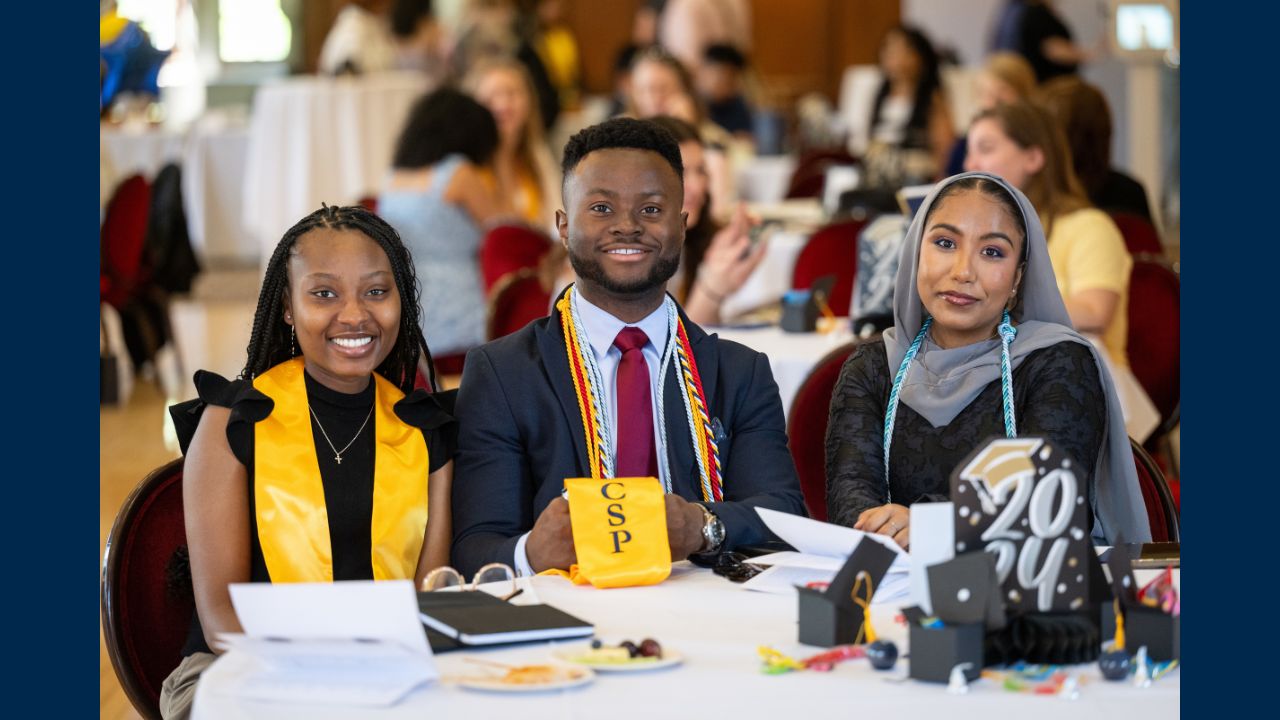 Three Comprehensive Studies students sit at a graduation banquet