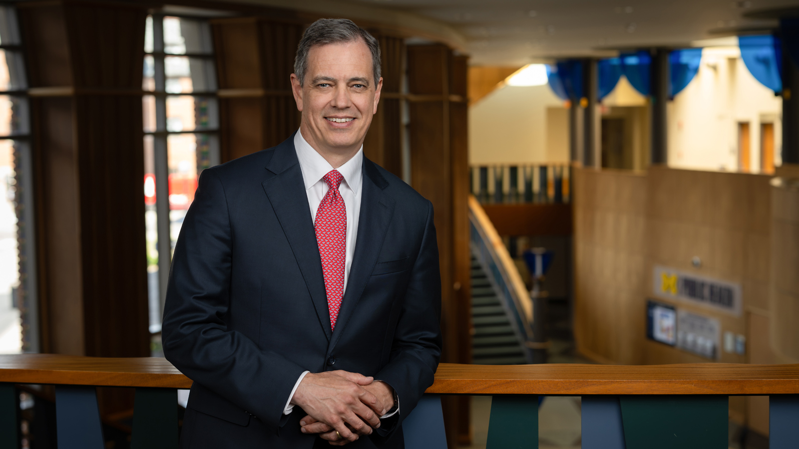 Dean Charles Holmes smiles while leaning against a balcony railing.