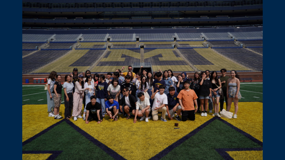 Students from the Nam Center pose on the field at the Big House