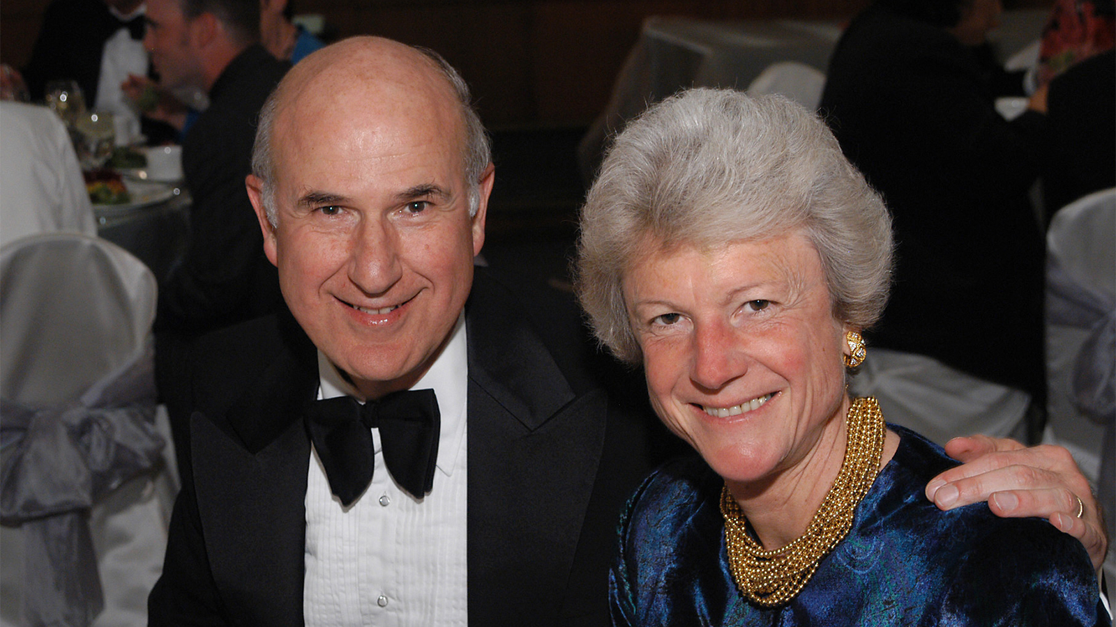 A photo of Dr. Gilbert Omenn with his hand on his wife’s shoulder.