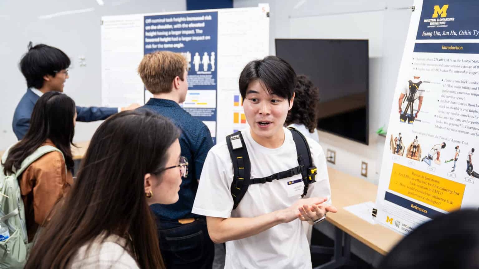 A person presenting at a poster session to an attentive listener.