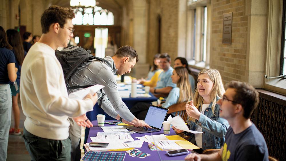 Students talking to other students at information tables about voting at an event at the Law School.