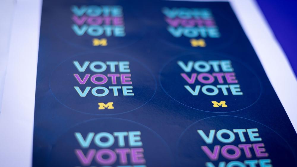 Stickers that say "Vote" and have the University of Michigan block M.