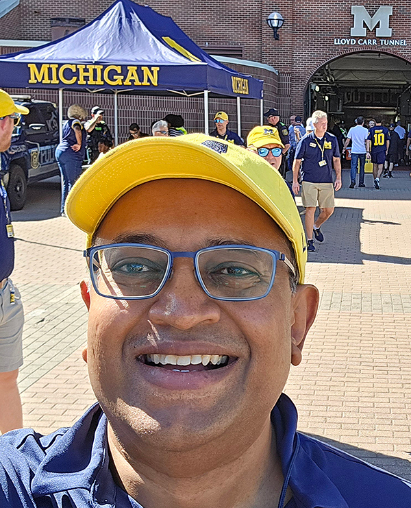 Headshot of Vikram Polavarapu in front of the Big House