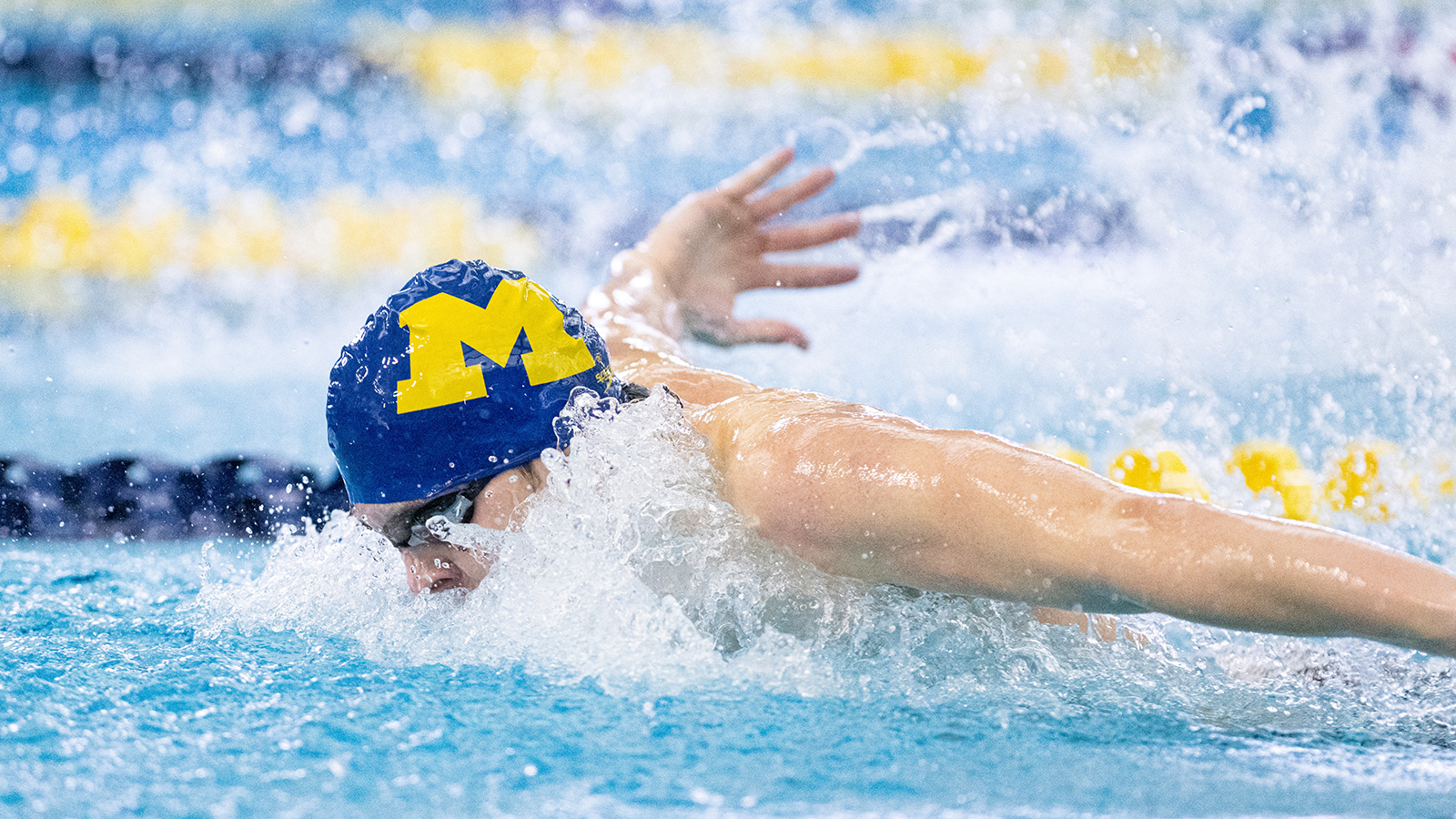 Juan Ceresa in the pool swimming the fly with goggles on and a Michigan swim cap.