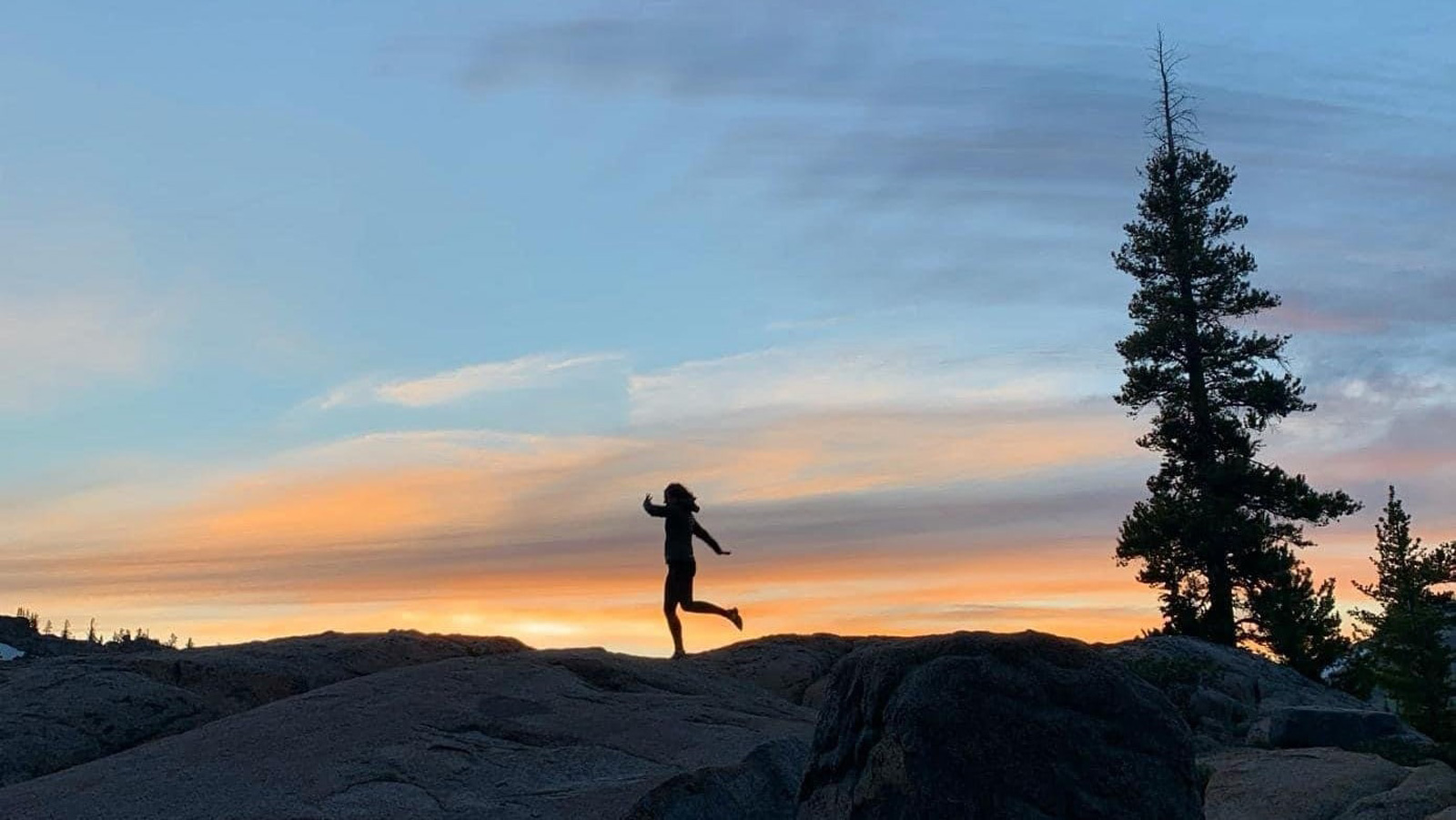 Julia Elkin running across rocks at sunset.