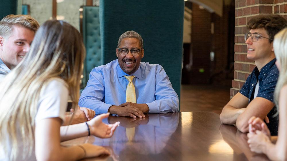 Martino Harmon sitting at a table with students.