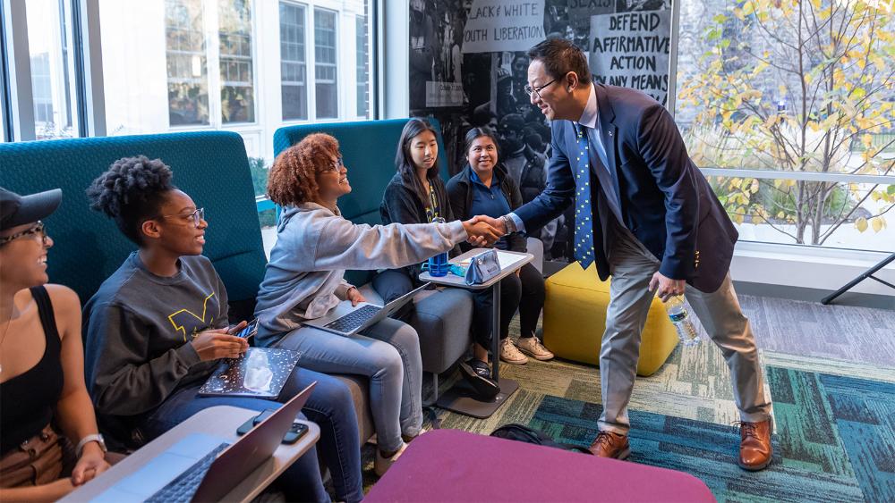 President Ono shaking hands with students studying in a lounge.