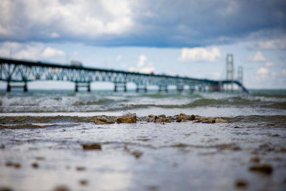 Rocks on the Mackinac shore are in focus. Out of focus in the background is the Mackinac Bridge.