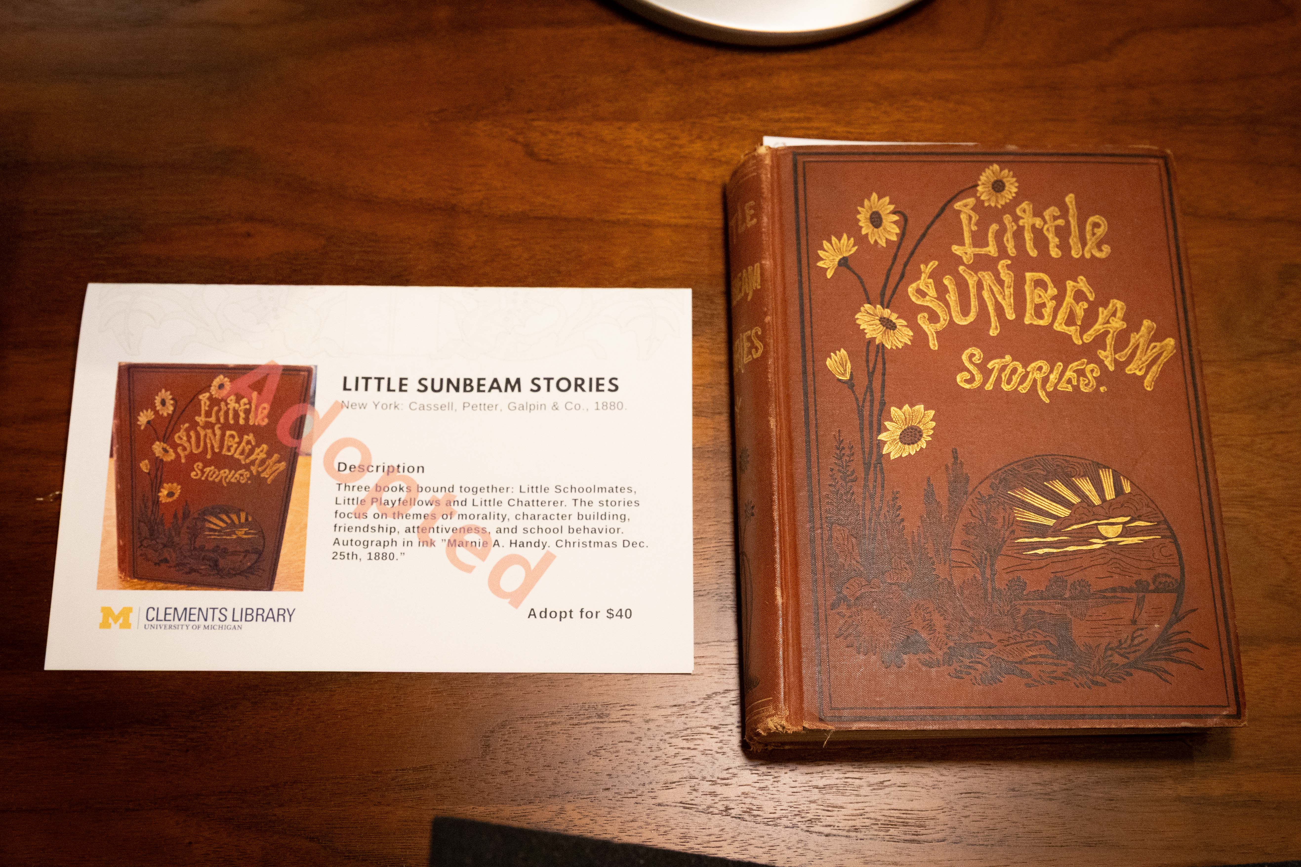 A description card stamped “adopted” next to a book.