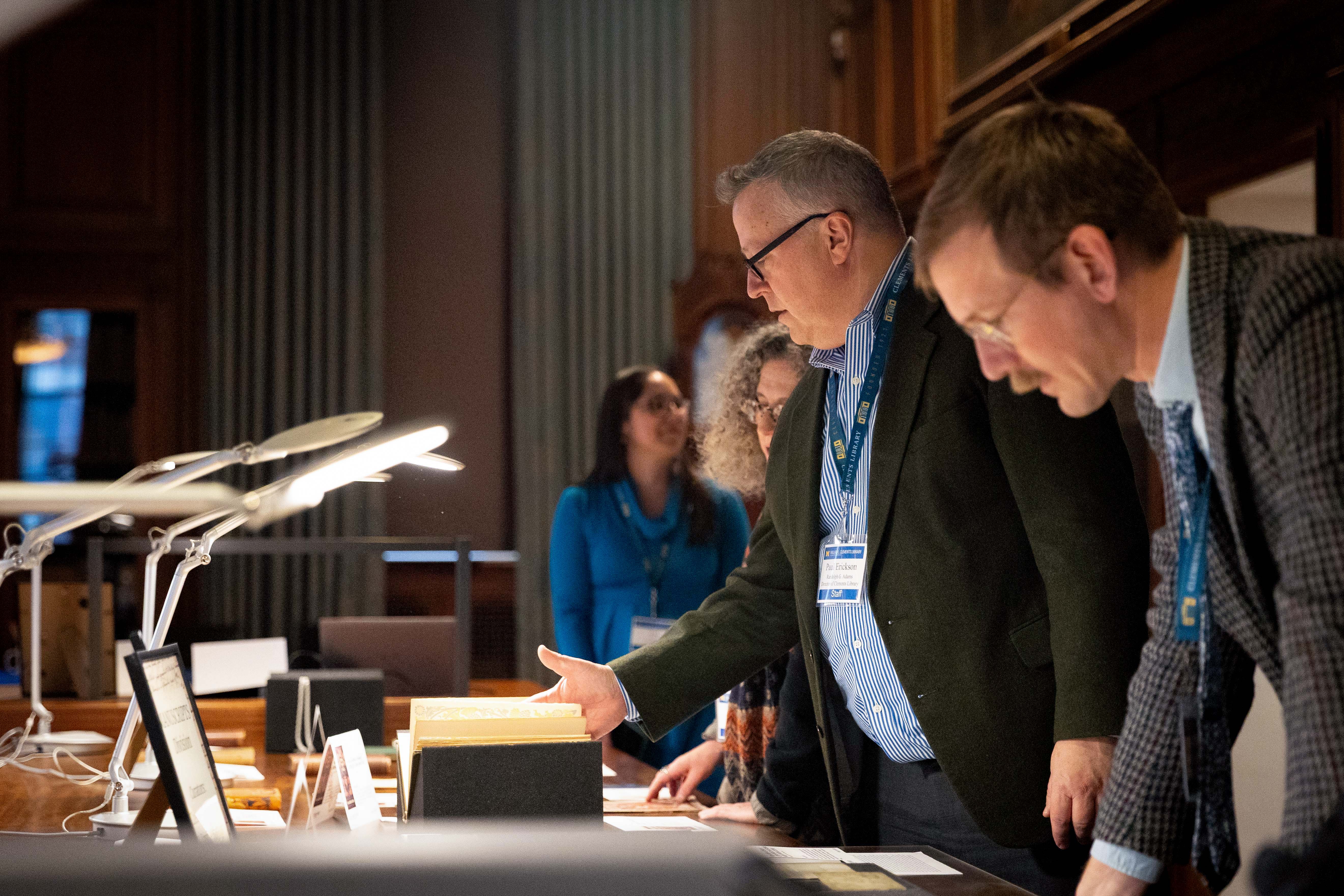 A line of people inspecting various objects on a table.