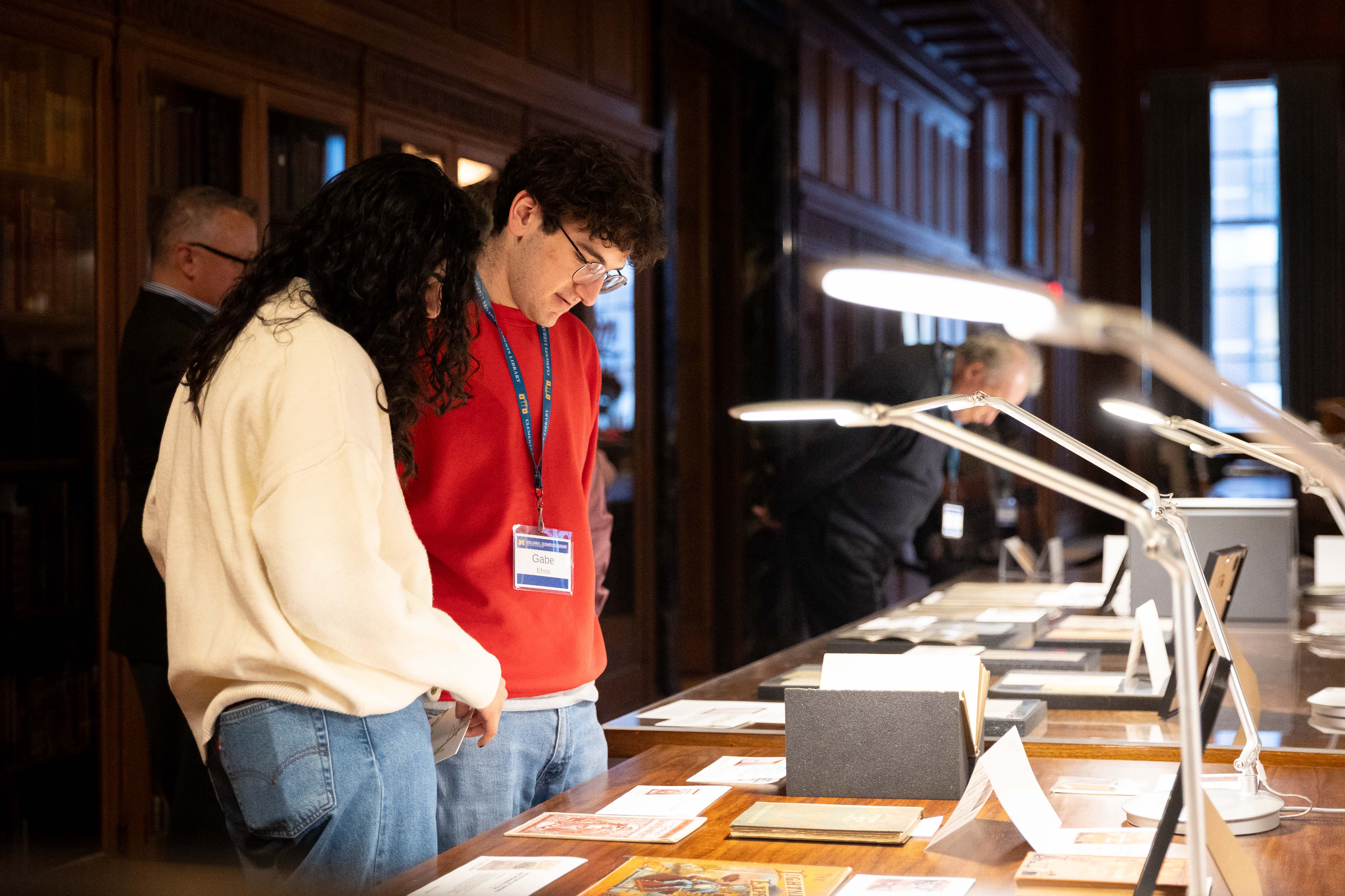 Two young people standing close to each other looking at a paper on a table.