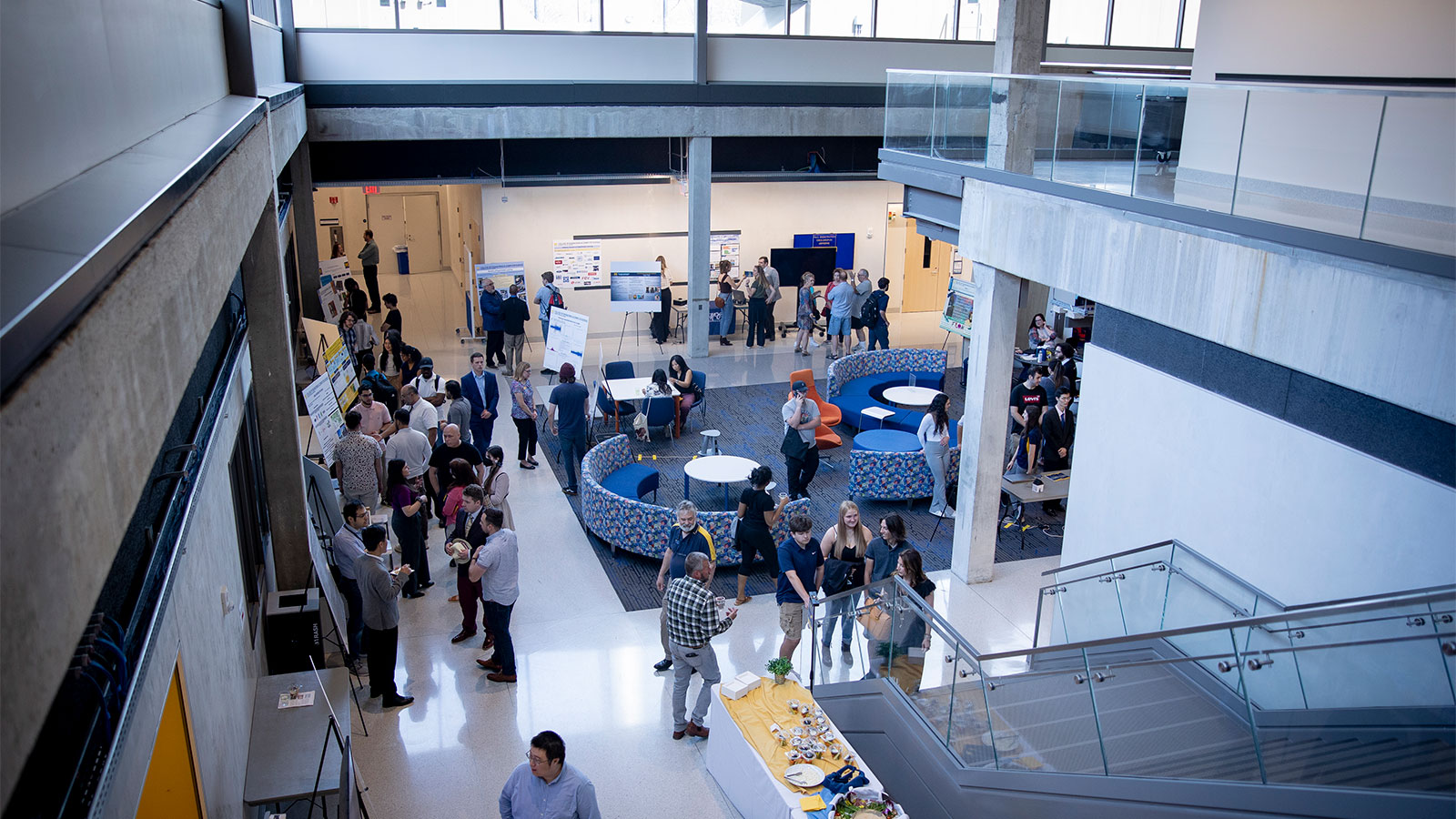 An overhead shot of an exhibit space with people, posters, and food.