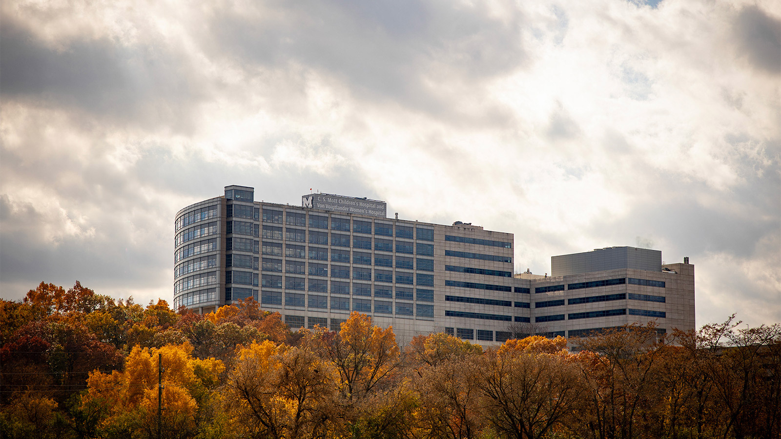 The exterior of C.S. Mott Children’s Hospital with trees that have yellow leaves in the foreground. 