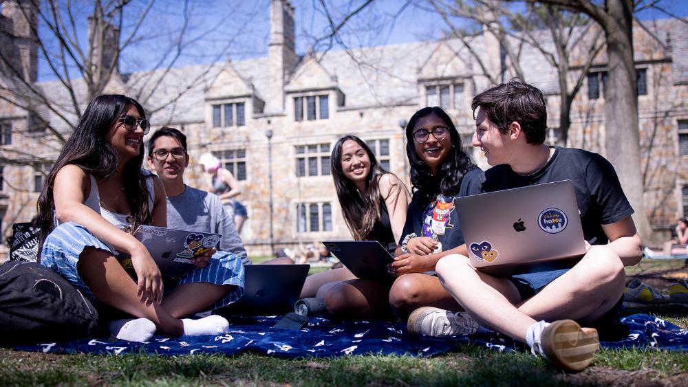 Five students sitting and chatting on campus.