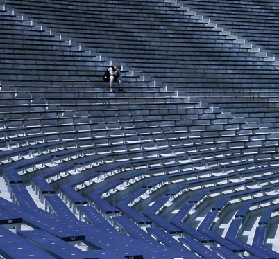 Student athlete sits alone in an empty stadium.