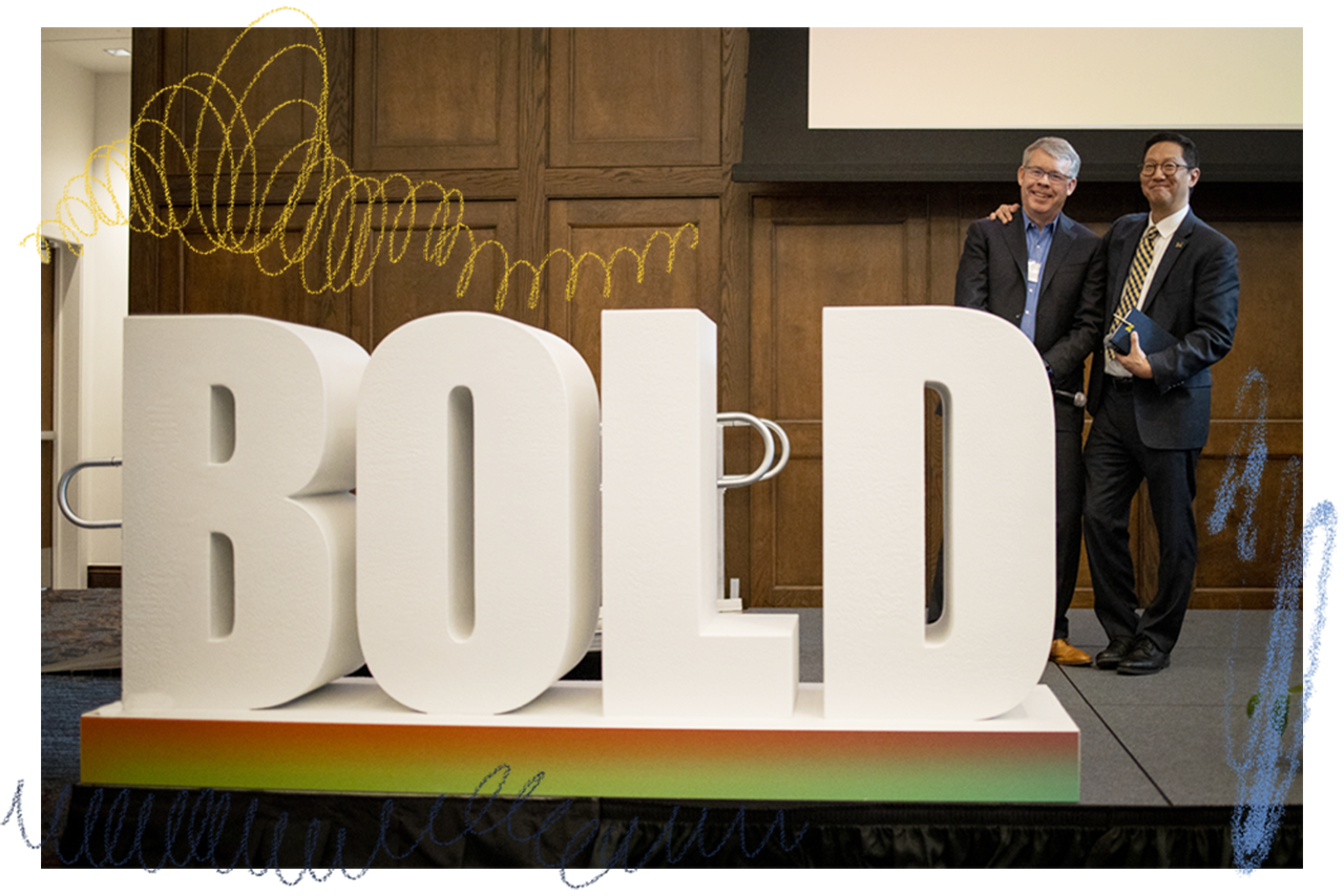 President Ono with Vice President for Development Tom Baird at the Bold Ideas summit standing in front of sculptural letters spelling the word BOLD.