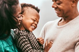 A close-up of Hudson holding Charlie, the family smiling.