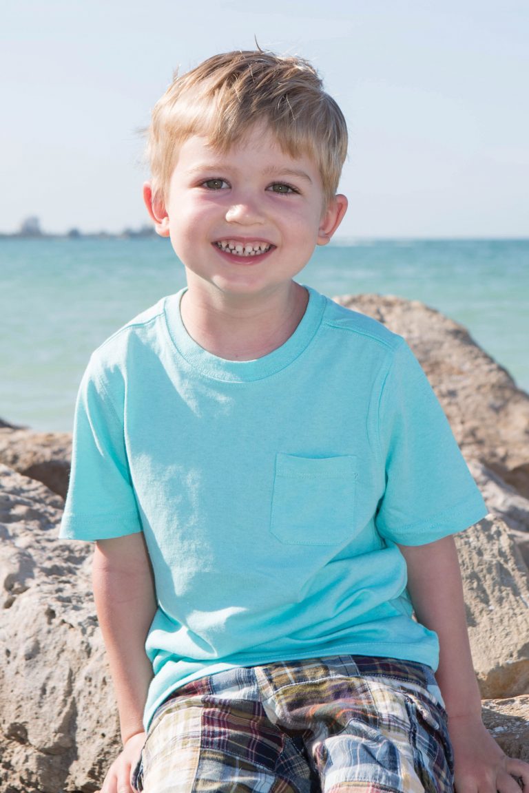 Chad Carr sits on a rock by the beach.