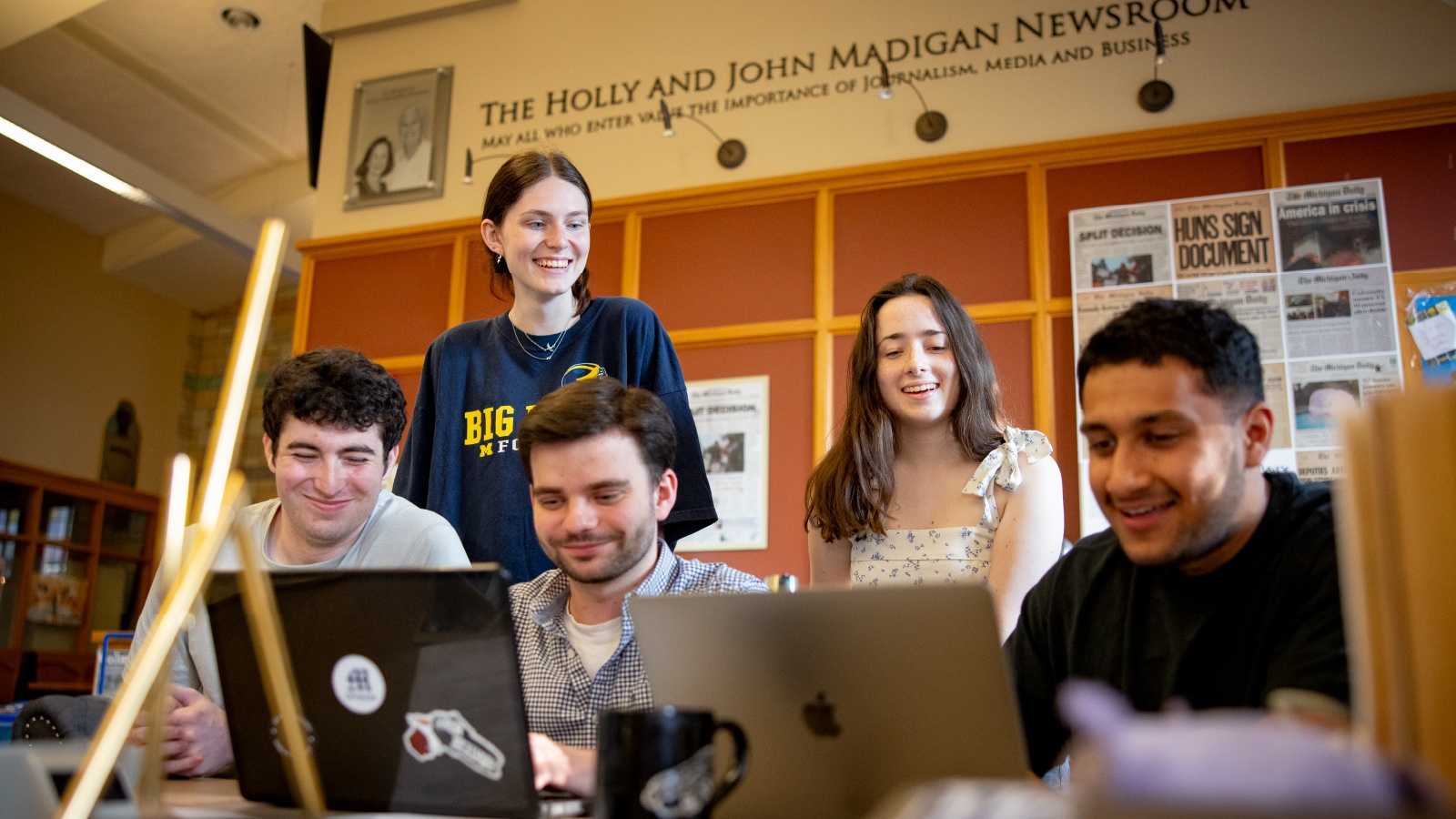 A group of five students gathered around laptops at The Michigan Daily office.