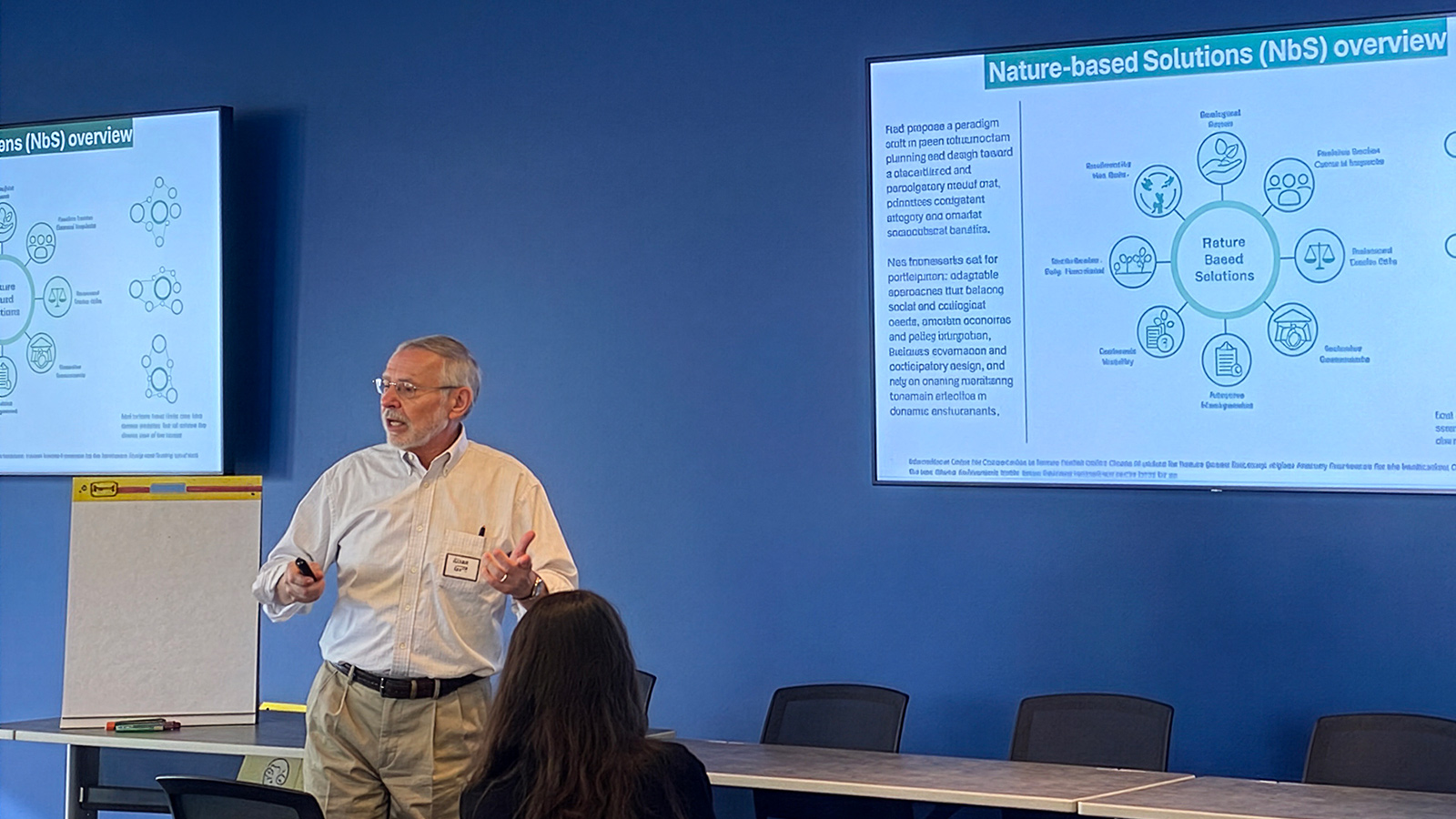 Glen Daigger presenting in front of screens detailing nature-based solutions to severe weather.