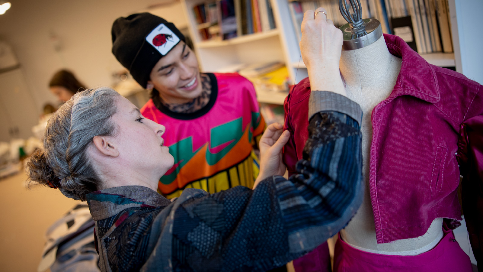 A professor and a student working on a piece of clothing.